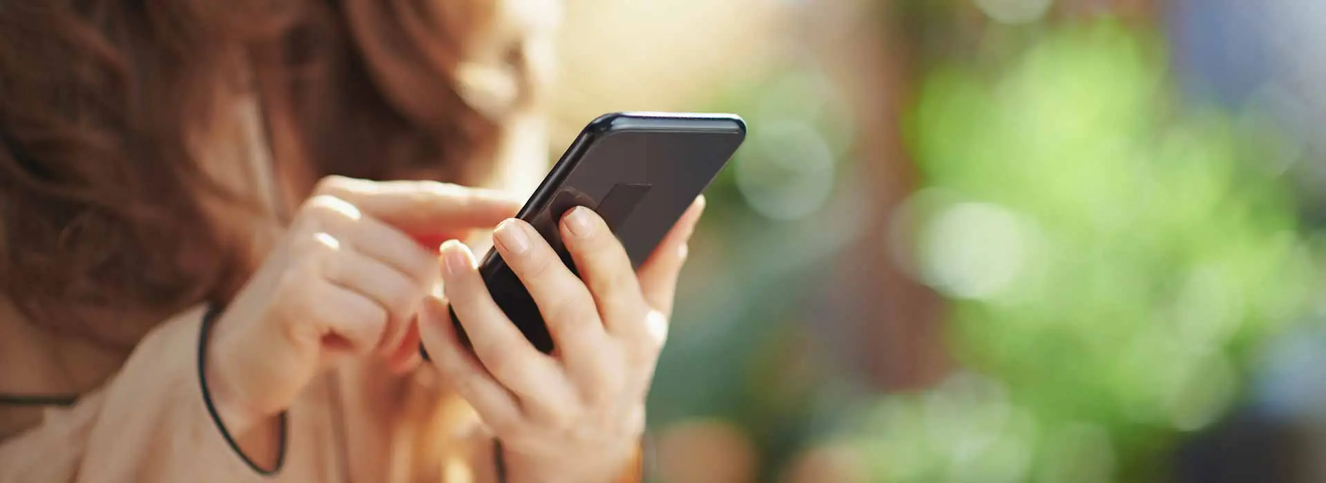 Frau hält Handy in der Hand und tippt