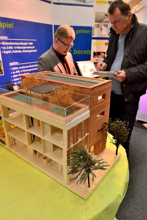 ein Modellhaus steht vor einem beratenden Menschen