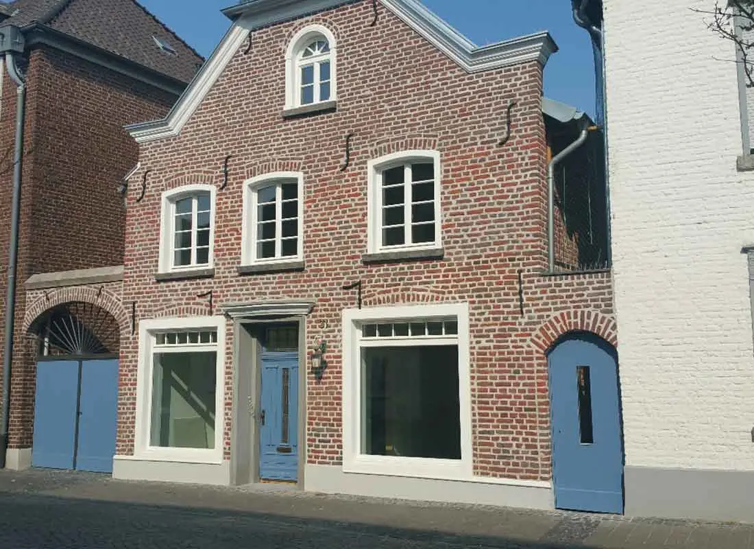 A two-story brick building directly touches the neighboring houses and has two large storefronts to the left and right of the center entrance door.