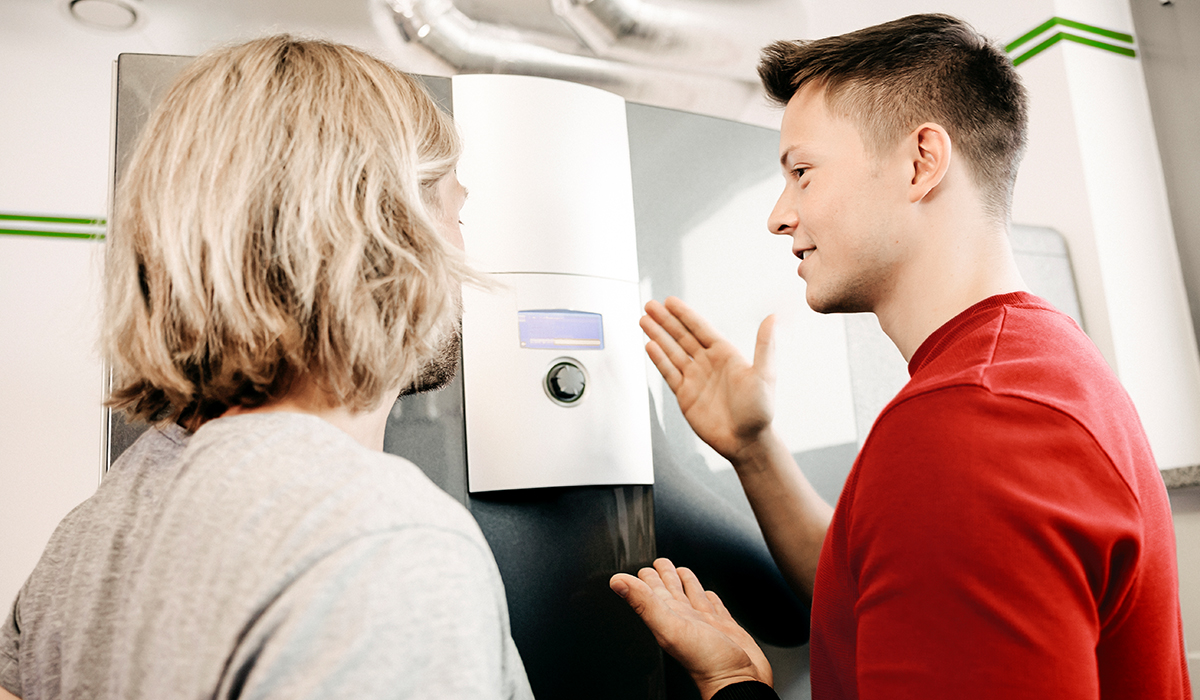 Eine alpha innotec Experte erklärt einem Hausbesitzer eine Wärmepumpe