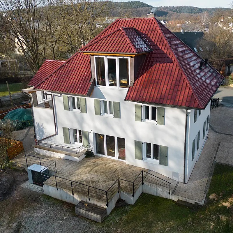 Eine moderne Luft/Wasser Wärmepumpe steht vor einem historischen Altbau