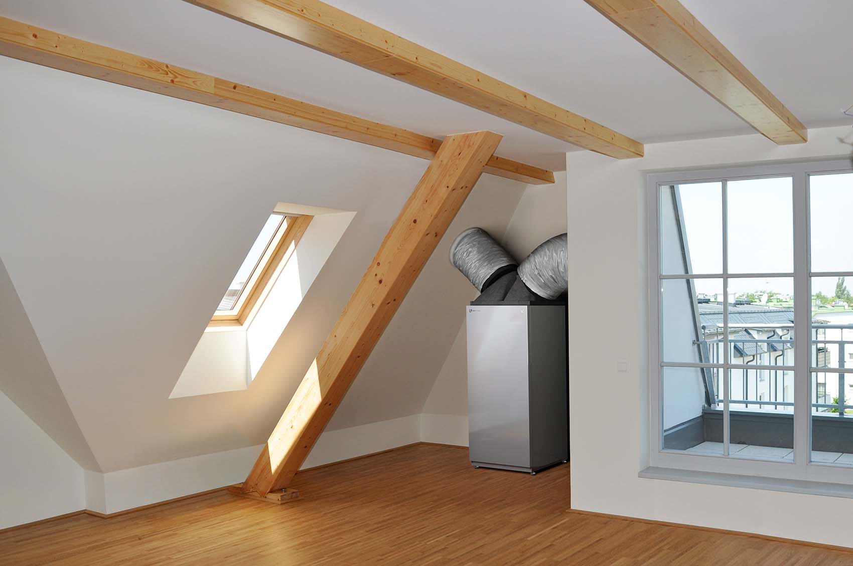 The heat pump Paros can be seen indoors, installed on the attic floor, with air ducts extending into the walls on its left and right side.