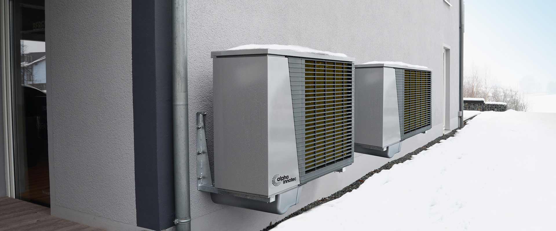 Two air/water-heat pumps LWD are installed outside next to each other, surrounded by snow.