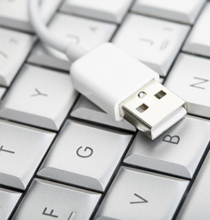 You see a close-up of a USB cable lying on a keyboard.