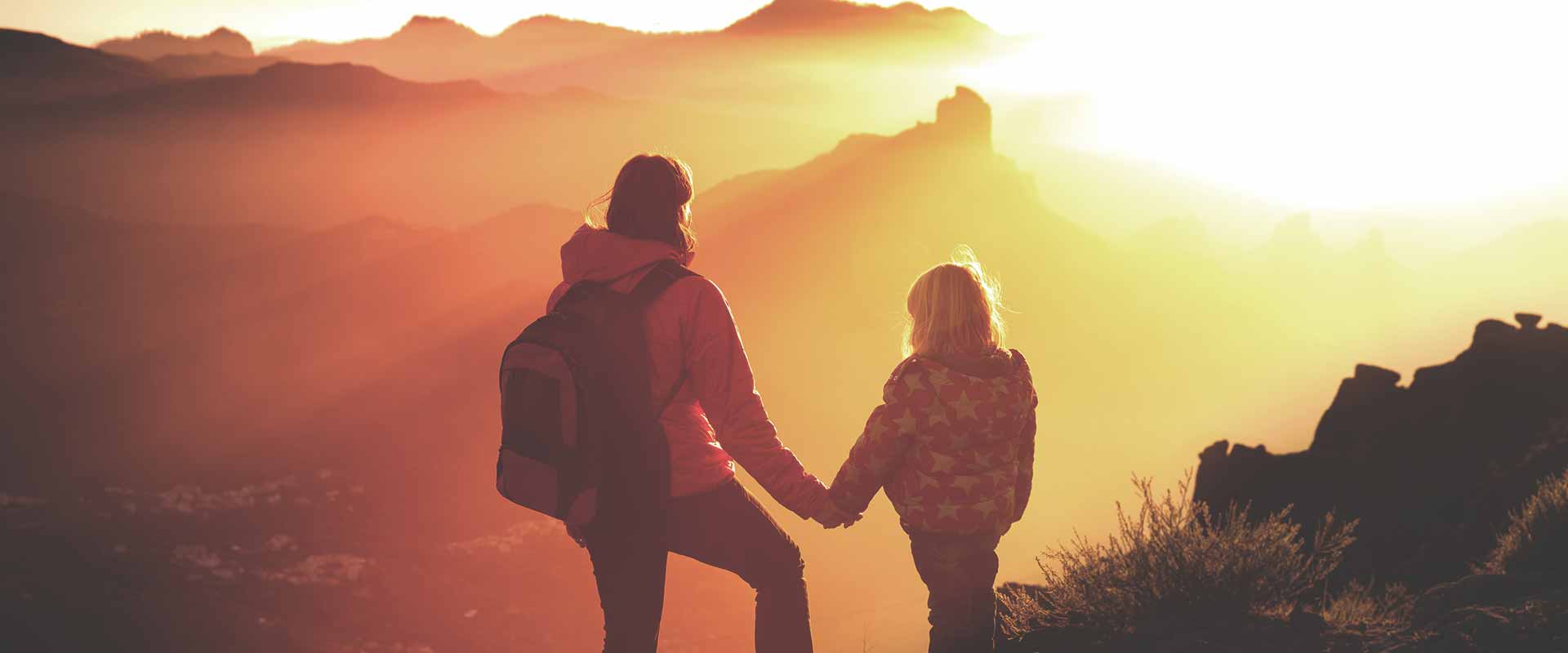 Kind und Frau stehen auf Berg und blicken in die Ferne