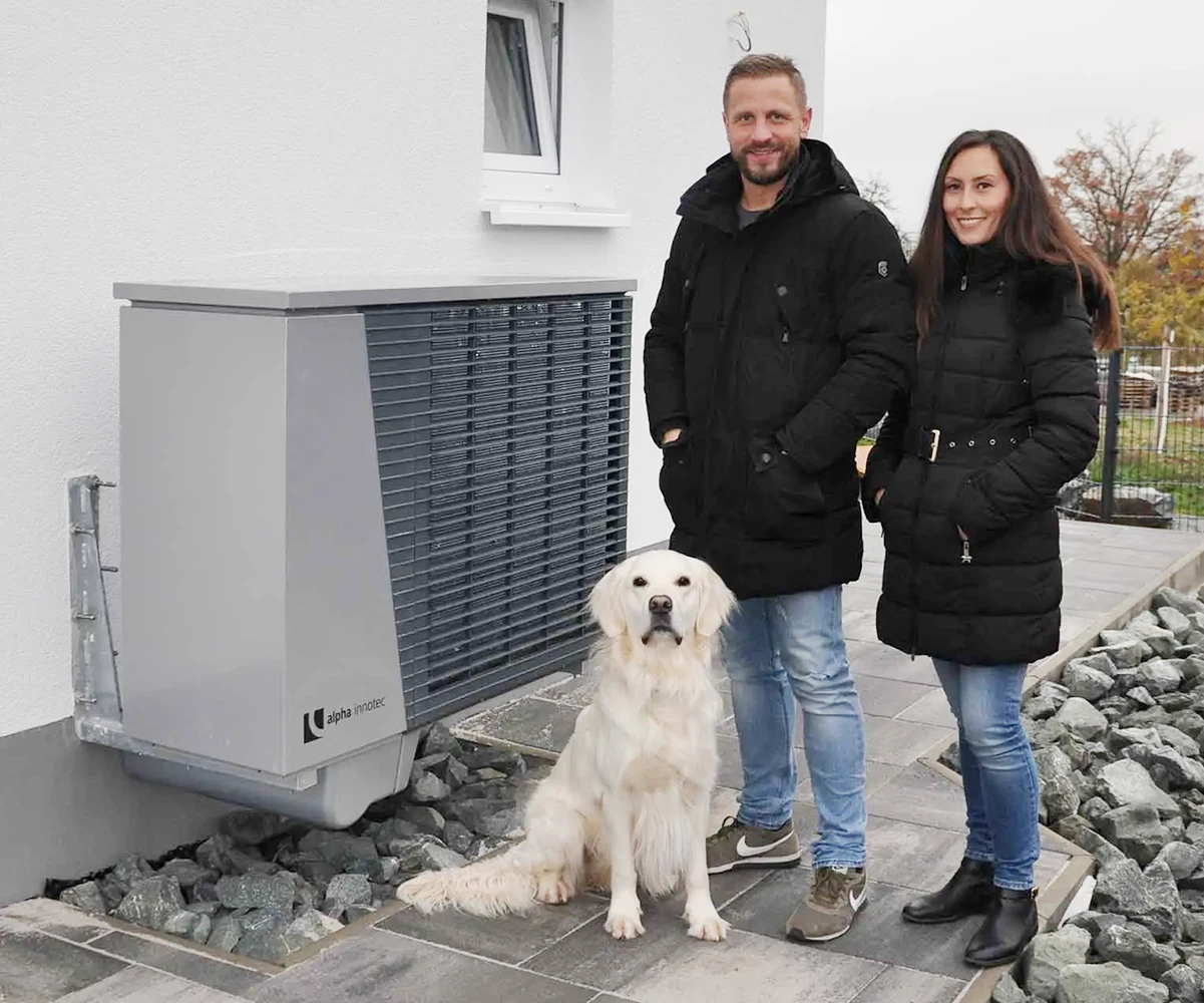 Famile Hohla steht neben ihrer alpha innotec Luftwärmepumpe